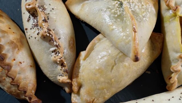 Traditional pastry empanada stuffed with various meat fillings close-up.