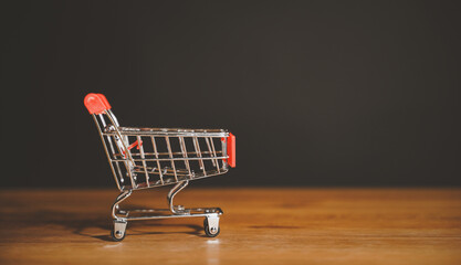 Shopping cart trolley on wood table black background. Concept e-commerce, marketplace, buy or...