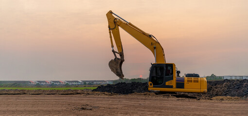 Excavator working on construction site at sunset background