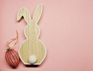 wooden rabbit or easter bunny made of wood with an pink easter egg on a pink background, colour of the year 2022 , top view, easter bunny, copies space