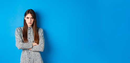 Angry frowning woman in dress, cross arms on chest and feel offended about something unfair,...