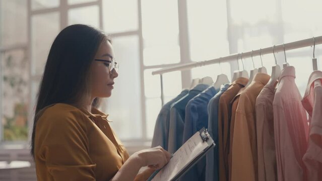 Young Asian woman making inventory, working on customer orders, retail business