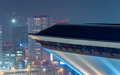 Katowice city panorama. A fragment of the "Spodek" sports hall in the foreground. The illuminated city in the background