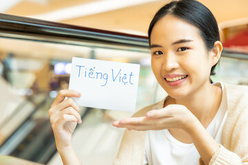Smiling woman showing Vietnamese vocab flash card, concept of southeast asian foreign language...