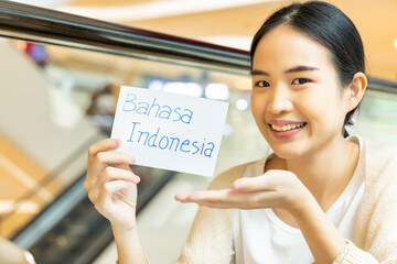 Smiling woman showing bahasa Indonesia, Indonesian language vocab flash card, concept of southeast...