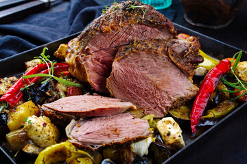 Traditional Greek barbecue leg of lamb with vegetable and feta cheese served as close-up on a rustic tray © HLPhoto