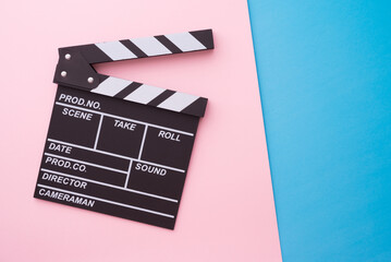 Naklejka premium Cinema clapperboard on pink blue colorful background - Movie cinema entertainment concept.