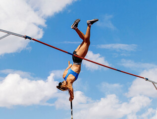 woman athlete in pole vault background blue sky - obrazy, fototapety, plakaty