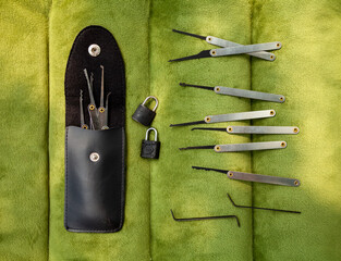 Many lock picking tools in a case, tension wrenches and 2 little padlocks flat lay. A kit of lock...