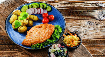Pork cutlet coated with breadcrumbs with potatoes and salads