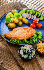 Pork cutlet coated with breadcrumbs with potatoes and salads