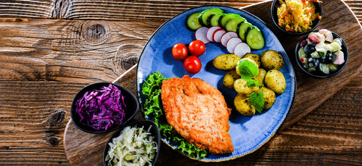 Pork cutlet coated with breadcrumbs with potatoes and salads