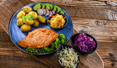 Pork cutlet coated with breadcrumbs with potatoes and salads