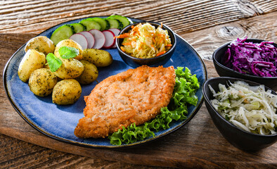 Pork cutlet coated with breadcrumbs with potatoes and salads