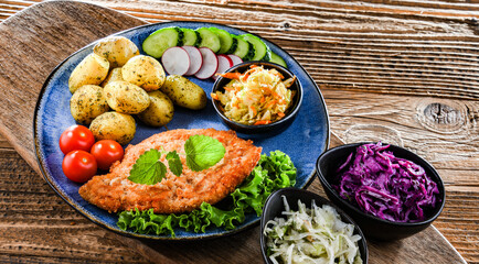 Pork cutlet coated with breadcrumbs with potatoes and salads