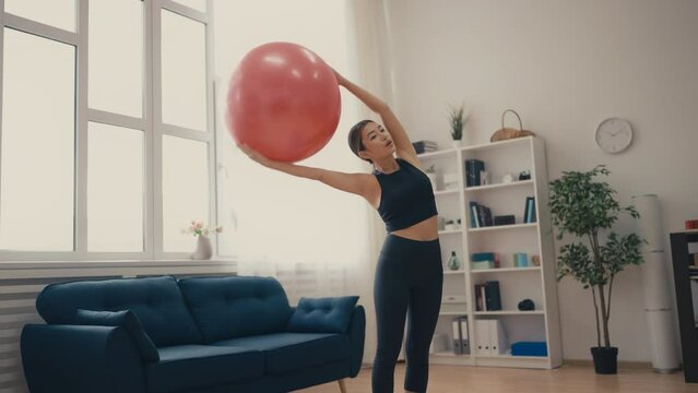 Young slim woman in sportswear doing exercises with fitball, active lifestyle
