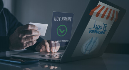 Man behind computer purchase food online. Credit card in hand. Home delivery, catering concept.