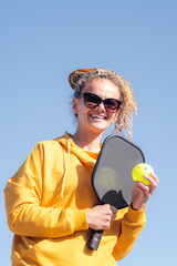 portrait woman player pickleball game over blue sky, pickleball yellow ball with paddle, outdoor...