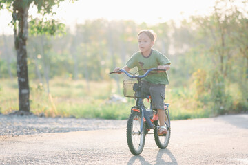 Naklejka premium Cute little boy riding bicycle in the park at sunset time.