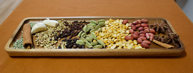indian spices on a wooden plate on an orange background, close up