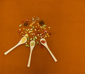 spices on wooden spoons on orange background