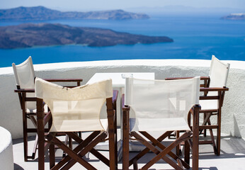 A small table and four chairs with scenic view of caldera santorini 