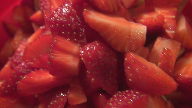 Red strawberries in a red bowl ready to eat . strawberries are already quadrisected . Half quartered fruits and berries juicy and yummy . very close makro close up of strawberry concept . red foods .
