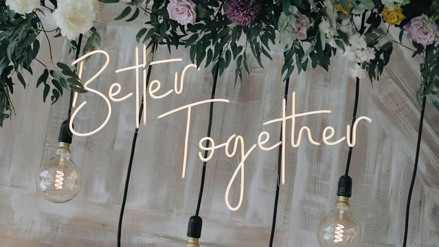 The inscription "better together" is decorated with light bulbs and flowers. Festive installation