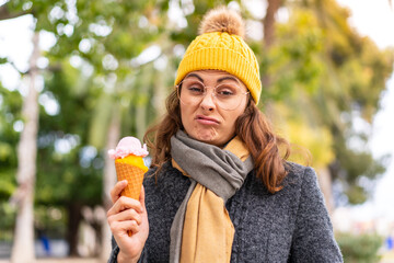 Fototapeta premium Brunette woman with a cornet ice cream at outdoors with sad expression