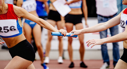 women relay team passing of baton running 4x400 meters - obrazy, fototapety, plakaty