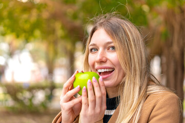Young pretty blonde woman with an apple at outdoors