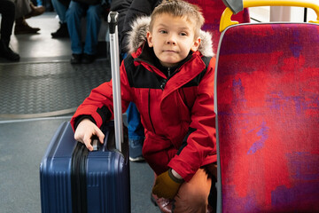 a boy with suitcase on bus or tram or train goes on trip..