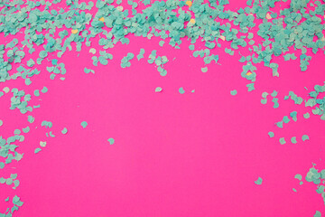 Confetti blue scattered on pink background. Carnival party. Ad template, space. Overhead view.