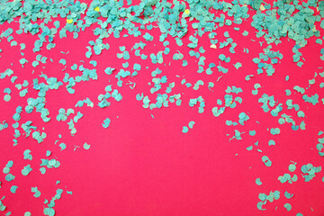 Confetti blue scattered on pink background. Carnival party. Ad template, space. Overhead view.