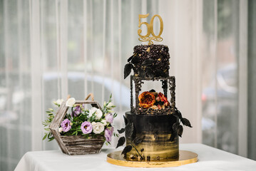 Birthday Cake. Cake for the 50th anniversary of the decorated flowers and gold and black decor. The...