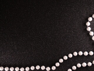 White beads on black sparkle background. Shimmering texture. Night party, new year, birthday. White balls on black shining material