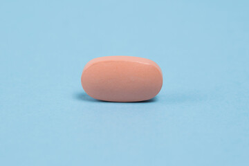 Pink pill macro on blue paper background with copy space