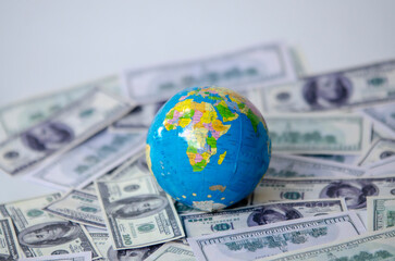 Globe over many American dollar banknotes.Economy background with abstract stock market graph, tickers, financial data and blue world map. Wallpaper for the global economy and financial news.