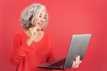 Mature woman celebrating while using a laptop