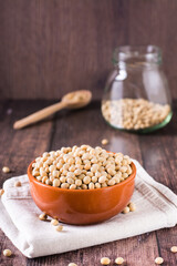 Raw soybean seeds in a bowl, spoon and jar on the table. Source of vegetable protein. Vertical view