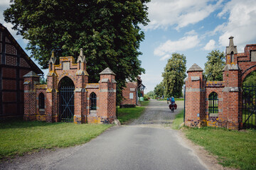 Bikepacking-Abenteuer - Frau fährt mit ihrem Rad durch das Tor eines alten Rittergutes in...