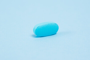 Vitamins in pills on blue paper background, medical capsule close-up