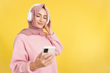 Muslim woman listening to music with headphones and a mobile