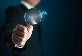 stock market for analysis technical grap. Businessman hand holding magnifier glass with virtual stock market chart, Business investment earning income