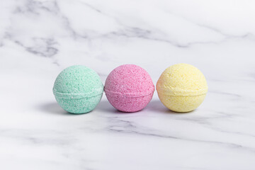 Three colorful bath bombs on marble background. Bath salts