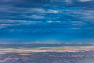 A view on Alazani valley in Kakheti region, Georgia. Caucasus mountains in the background. Dramatic sky. Clouds.