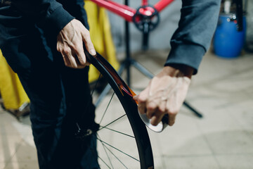 Mechanic repairman assembling tubeless wheel install tape sealant for bike tire custom bicycle in...
