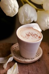 Kawa z pianką w białej filiżance i białe tulipany. Perfekcyjna kawa, cudowny poranek. Kawowy klimat na Dzień Kobiet