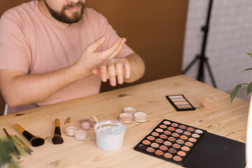Male beauty blogger testing cream and recording a video lesson his with mobile phone close-up-...
