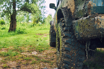 Fototapeta na wymiar Dirty SUV is standing on the lawn after an off-road race, covered in slush. A beautiful photo of nature and an SUV in a beautiful meadow. Rear view of the bumper and wheel protector of the vehicle